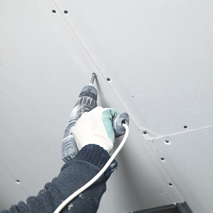contractor hand close up with drill installing drywall at ceiling kenner la