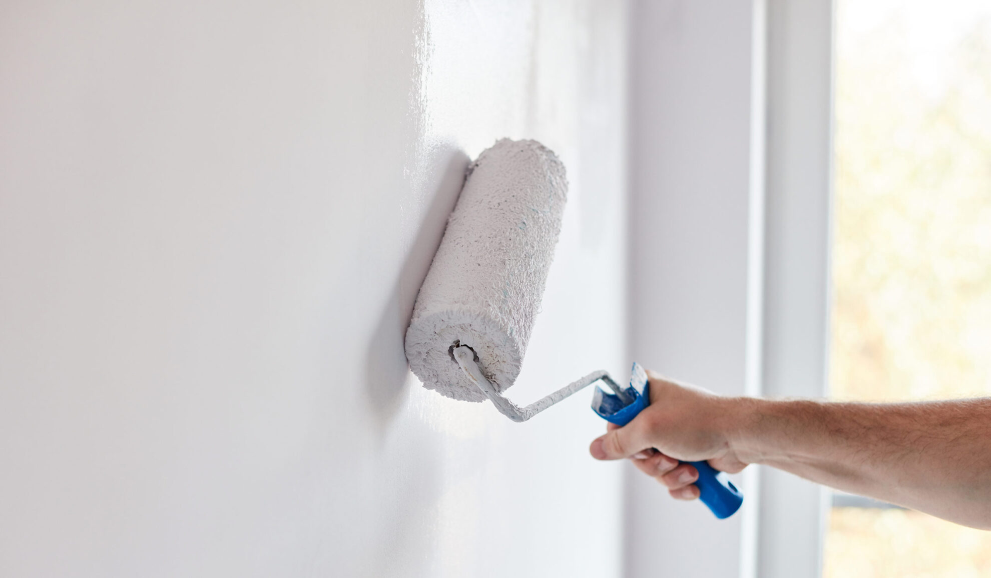 contractor hand with paint roller painting a white wall kenner la